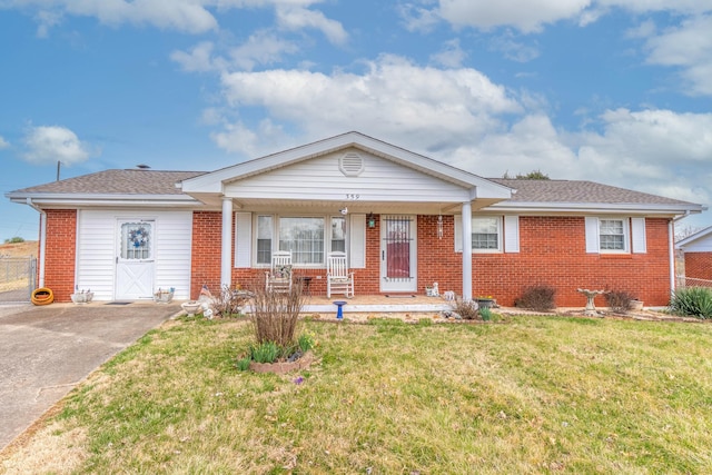 ranch-style home with covered porch, a shingled roof, a front lawn, and brick siding