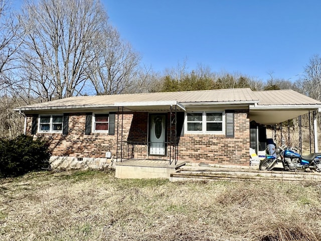 view of front of property with crawl space, metal roof, a carport, and brick siding