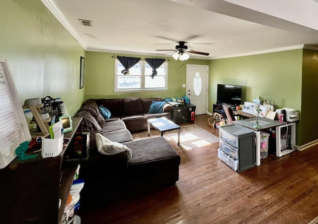 living area featuring visible vents, ornamental molding, a ceiling fan, wood finished floors, and baseboards