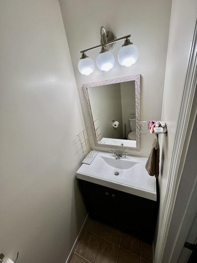 half bath with baseboards, toilet, vanity, and tile patterned flooring