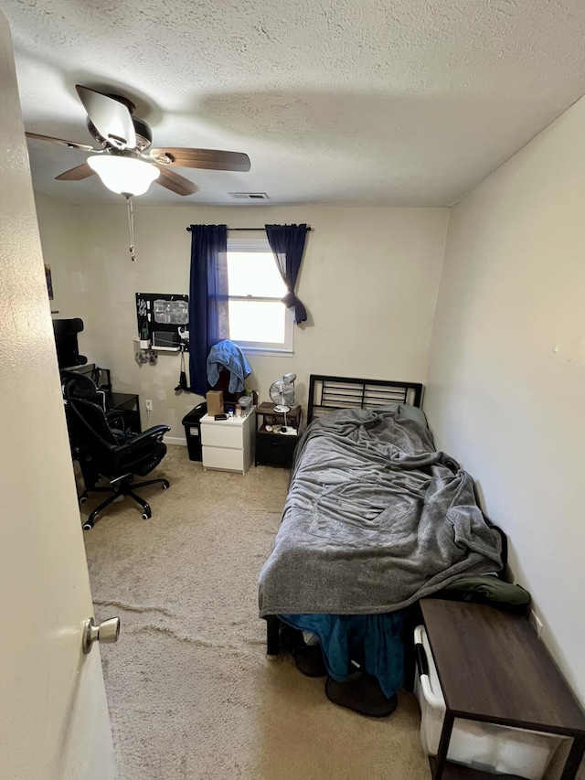 carpeted bedroom featuring visible vents, a textured ceiling, and ceiling fan