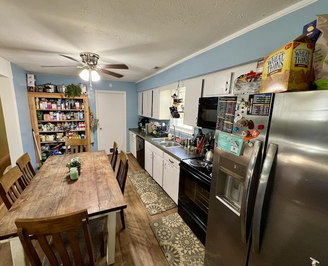 kitchen featuring white cabinetry, black appliances, wood finished floors, and a sink