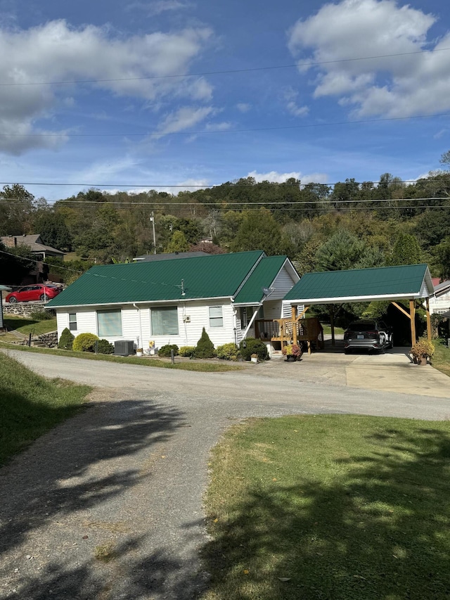 view of building exterior with driveway, a carport, and central AC