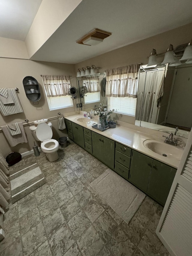 full bathroom featuring toilet, a sink, baseboards, and double vanity