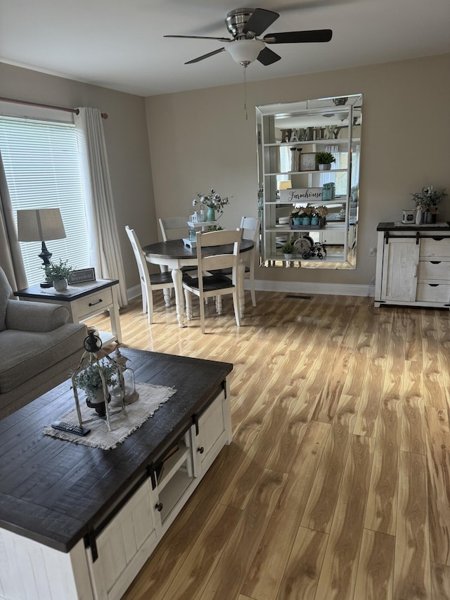 living area featuring ceiling fan, baseboards, and wood finished floors