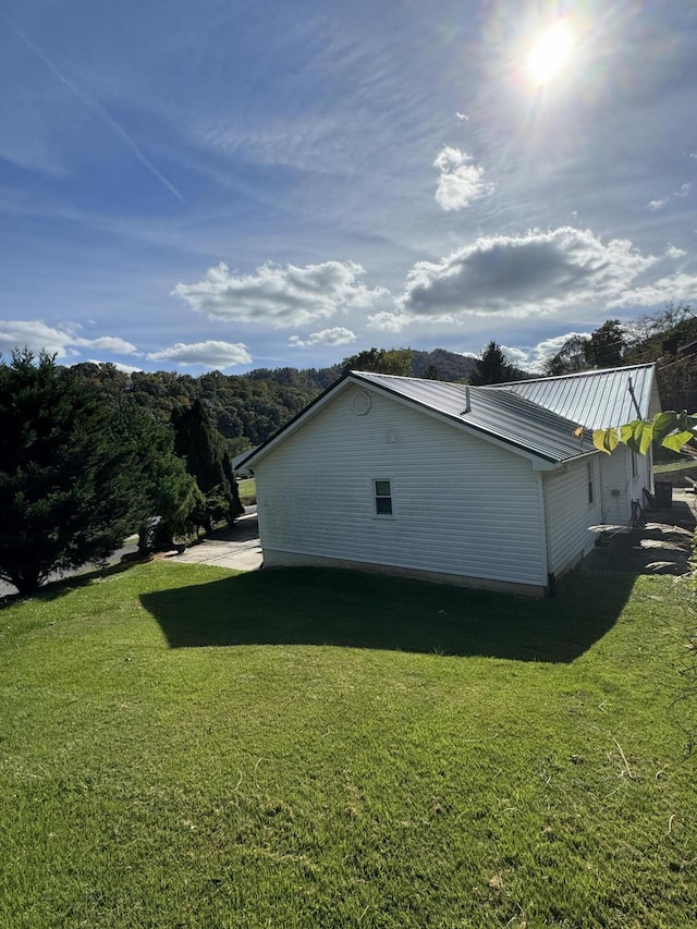 view of property exterior featuring metal roof and a lawn