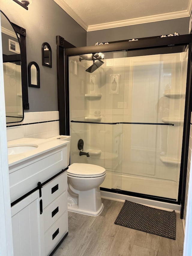 full bathroom featuring tile walls, ornamental molding, a stall shower, vanity, and wood finished floors