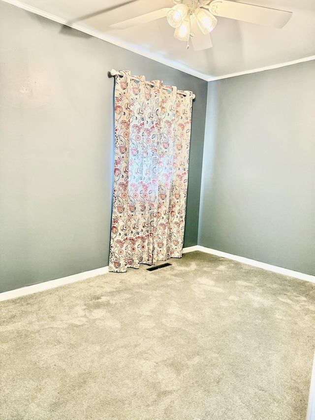 unfurnished room featuring ceiling fan, carpet floors, baseboards, and crown molding