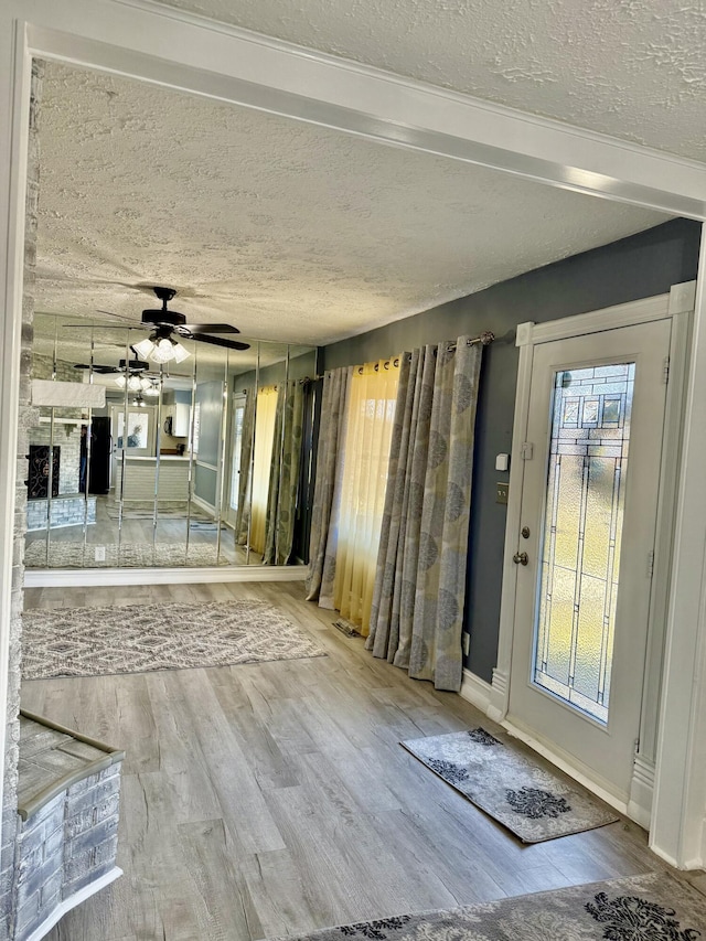 entryway featuring baseboards, a textured ceiling, a ceiling fan, and wood finished floors