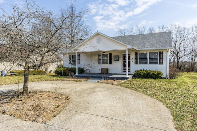 view of front facade with a porch, a shingled roof, a front lawn, and concrete driveway