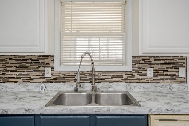 kitchen with a sink, tasteful backsplash, white cabinets, and white dishwasher