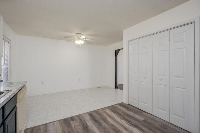 kitchen featuring dark wood-type flooring, light countertops, baseboards, dishwasher, and ceiling fan