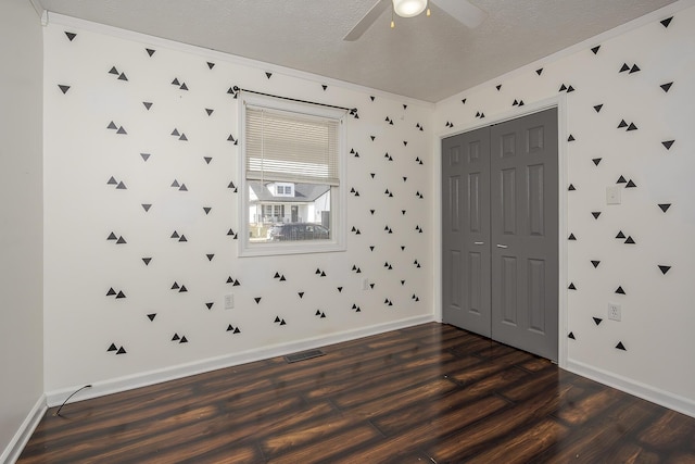 spare room with dark wood finished floors, crown molding, ceiling fan, and a textured ceiling