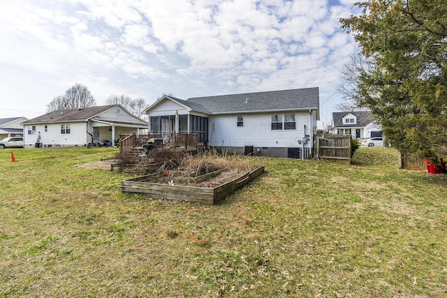 back of house featuring fence, a sunroom, a yard, a garden, and crawl space