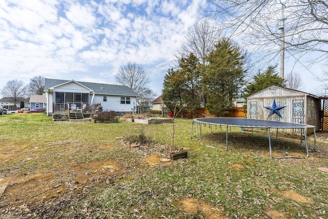 view of yard with a storage unit, an outbuilding, a trampoline, fence, and a sunroom