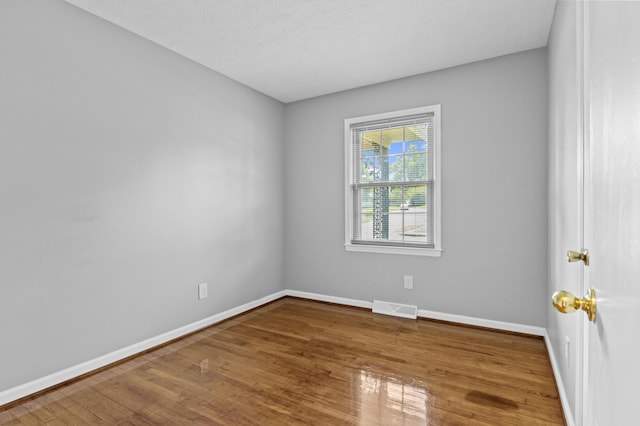 unfurnished room featuring visible vents, baseboards, and hardwood / wood-style floors