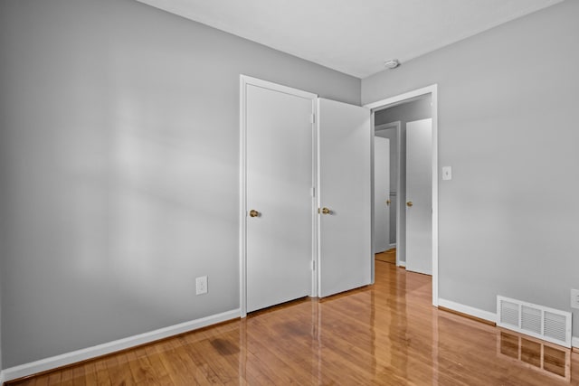 unfurnished bedroom featuring visible vents, baseboards, and hardwood / wood-style flooring