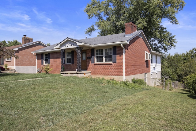 view of front of house with brick siding, a chimney, a front lawn, and roof with shingles