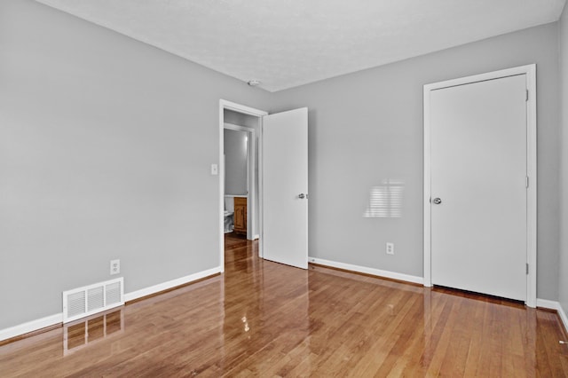 unfurnished room with visible vents, baseboards, and hardwood / wood-style flooring