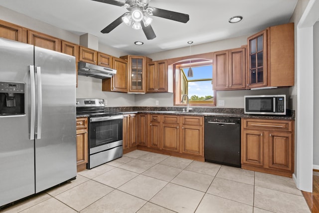 kitchen with brown cabinets, under cabinet range hood, a sink, stainless steel appliances, and light tile patterned floors