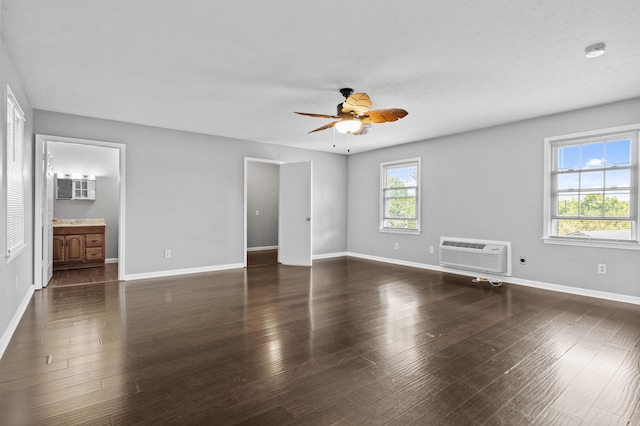 unfurnished bedroom featuring a wall mounted AC, baseboards, and wood finished floors