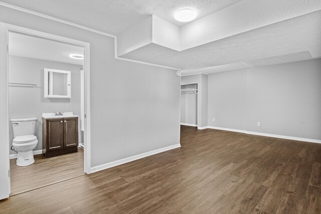 interior space with a textured ceiling, baseboards, and wood finished floors