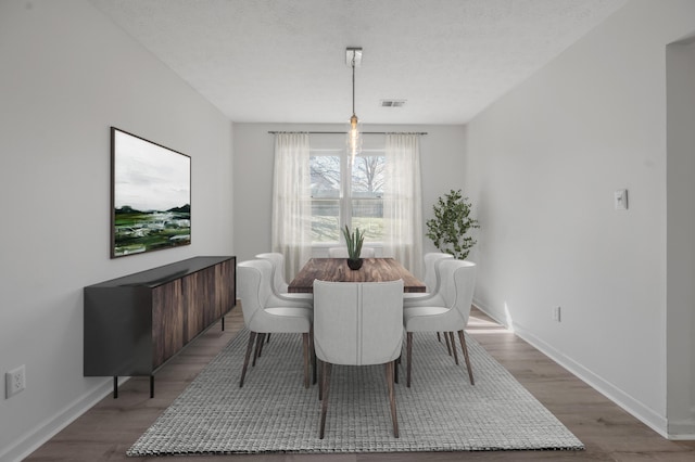 dining space with wood finished floors, visible vents, and a textured ceiling