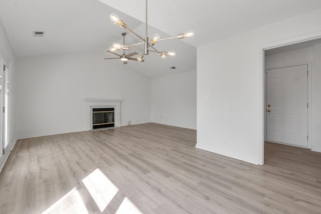 unfurnished living room with visible vents, an inviting chandelier, light wood-style flooring, vaulted ceiling, and a glass covered fireplace