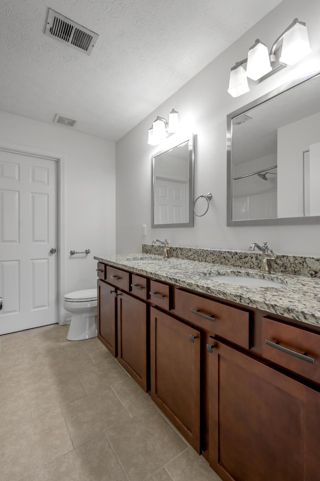 full bath with toilet, visible vents, and a sink