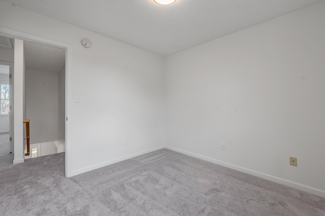 carpeted spare room with baseboards and a textured ceiling