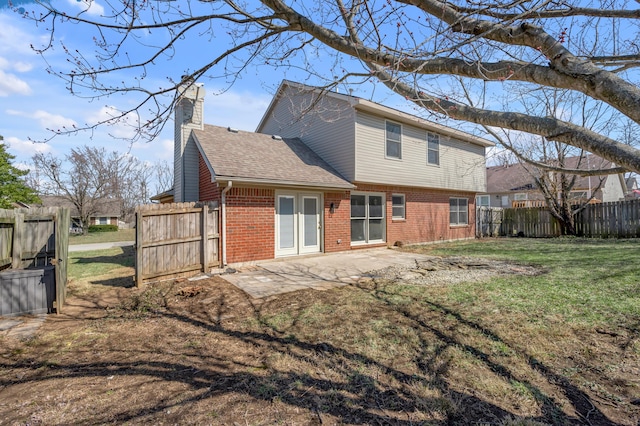 back of house with fence, a chimney, a patio area, a lawn, and brick siding