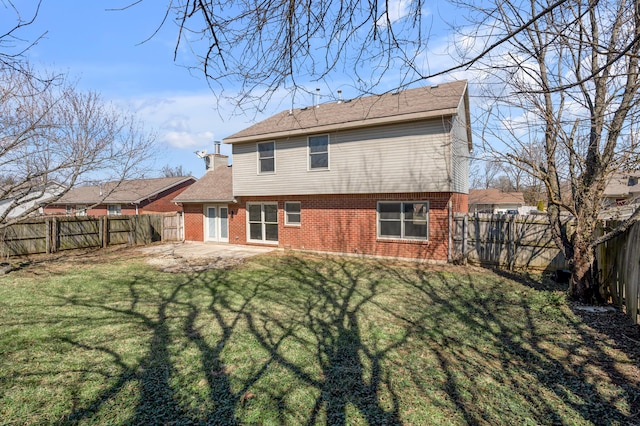 back of property featuring brick siding, a fenced backyard, a patio area, and a yard