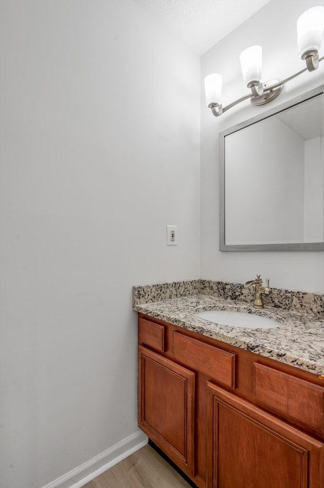 bathroom with vanity, wood finished floors, and baseboards