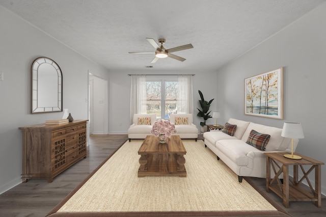 living area with baseboards, wood finished floors, and a ceiling fan