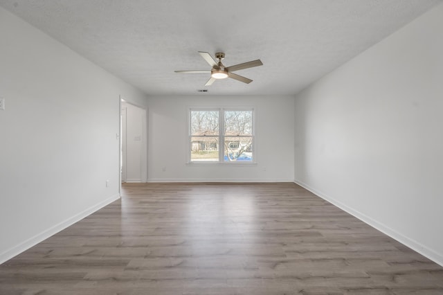 unfurnished room with a ceiling fan, wood finished floors, baseboards, and a textured ceiling