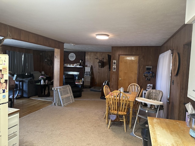 carpeted dining room with a fireplace and wood walls