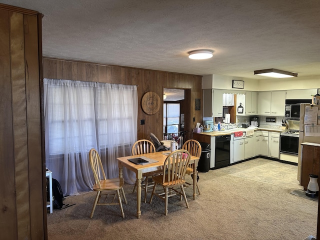 dining room with wooden walls, light colored carpet, and a textured ceiling