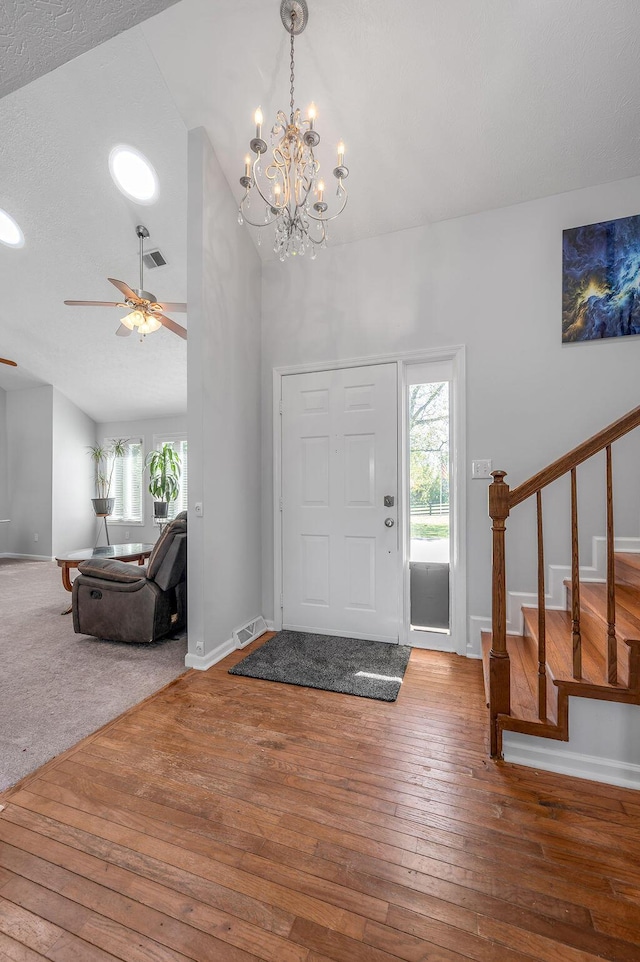 foyer entrance with stairway, baseboards, visible vents, and hardwood / wood-style flooring