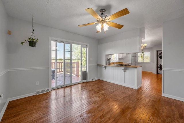 interior space featuring visible vents, white cabinetry, stacked washing maching and dryer, and wood-type flooring