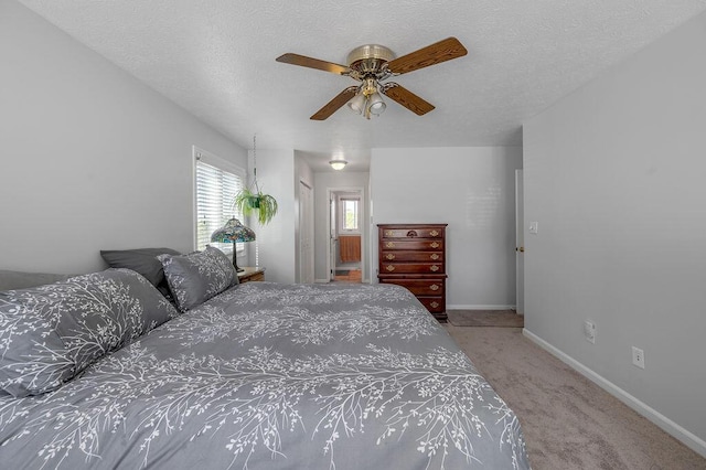 carpeted bedroom with a ceiling fan, baseboards, and a textured ceiling