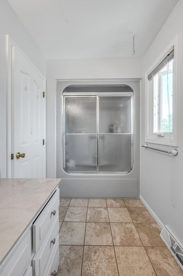 bathroom featuring tile patterned flooring, visible vents, baseboards, enclosed tub / shower combo, and vanity