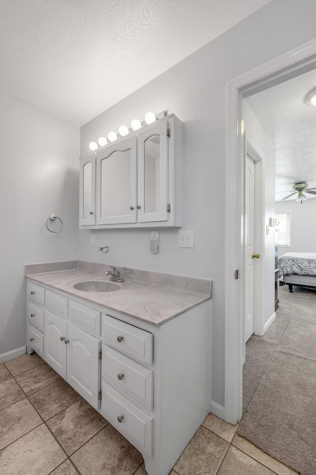 bathroom with a ceiling fan, a textured ceiling, ensuite bath, baseboards, and vanity