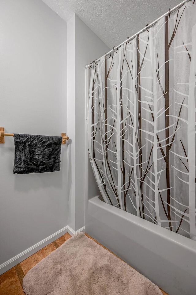 full bath featuring shower / bath combination with curtain, baseboards, and a textured ceiling