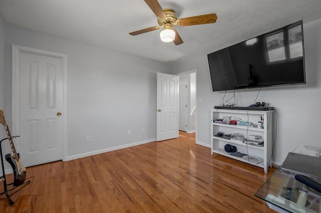 living room with a textured ceiling, baseboards, ceiling fan, and wood finished floors