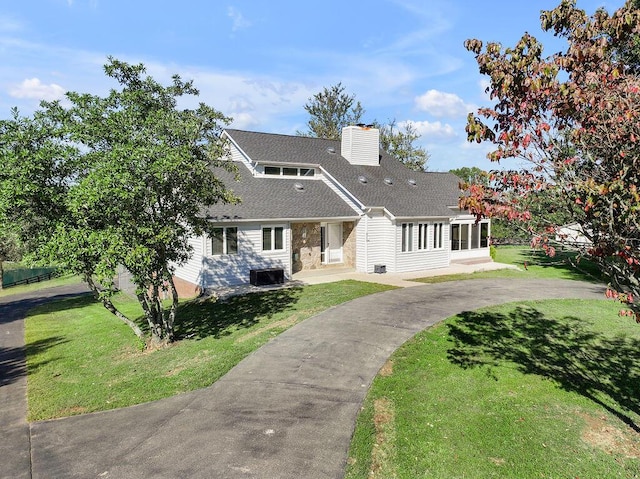 view of front of home featuring a shingled roof, a front lawn, and a chimney