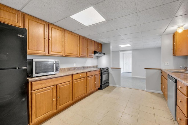 kitchen with black appliances, under cabinet range hood, a sink, light countertops, and baseboards