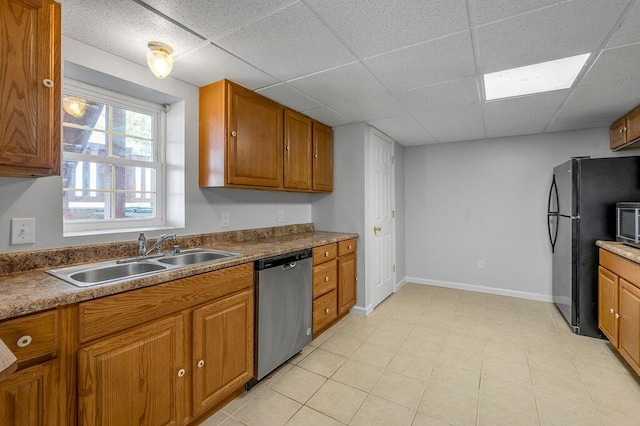 kitchen with a sink, a paneled ceiling, brown cabinets, and stainless steel appliances