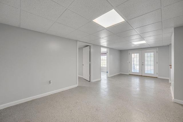 empty room featuring speckled floor, french doors, baseboards, and a drop ceiling