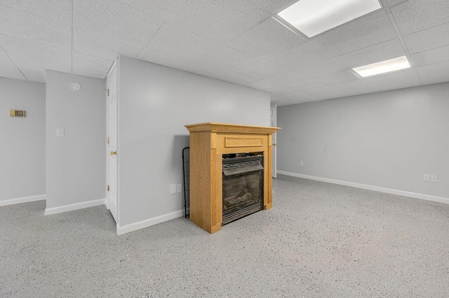 finished below grade area featuring baseboards, a paneled ceiling, and a fireplace