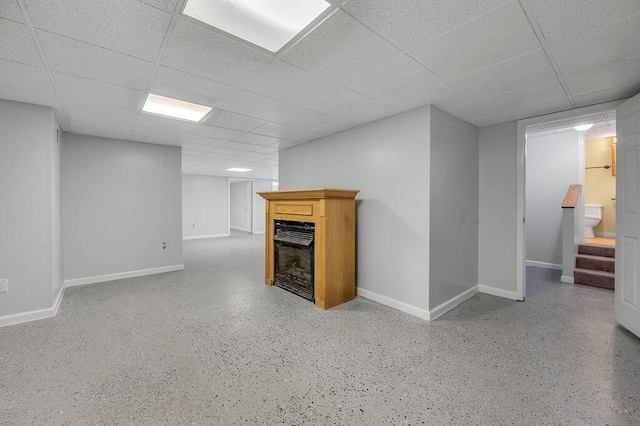 finished basement with stairway, a fireplace, a paneled ceiling, and baseboards